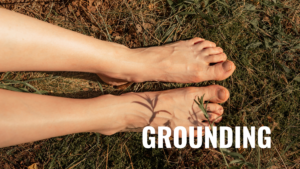 Foto de uma pessoa caminhando descalça na grama úmida, praticando grounding para equilibrar a energia vital